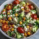 Bright cherry tomatoes, diced cucumber, and fresh herbs mingle in a bowl of High Protein Quinoa & Chickpea Salad.