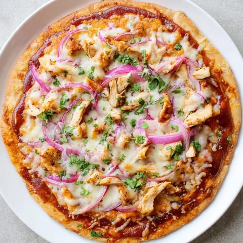 Sliced wedges of Chicken BBQ Pizza reveal tangy barbecue sauce, gooey mozzarella, and smoked gouda, perfect for a casual game day dinner.