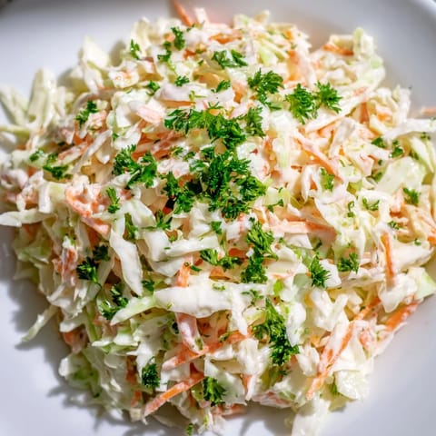 Coleslaw with Apple features crisp cabbage and carrot tossed in a light, tangy yogurt dressing, perfect for a backyard barbecue.