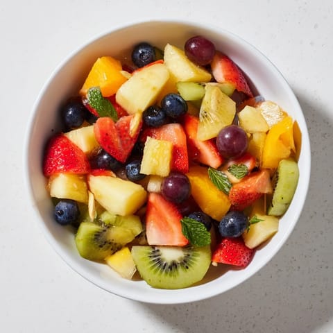 A close-up view of a chilled bowl of Fruit Salad, featuring juicy grapes and blueberries on a rustic kitchen counter.
