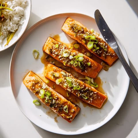 Four golden Honey Garlic Salmon fillets glazed in a glossy, sweet-savory sauce, served with fluffy steamed rice and vibrant green vegetables.