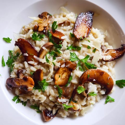 Spoon lifting a ladle of Roasted Mushroom Risotto from a pot, showing cheesy, creamy texture and tender caramelized mushrooms.