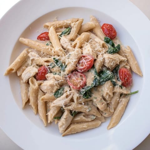A close-up view of Greek Yogurt Chicken Pasta, featuring golden chicken, whole wheat penne, and a sprinkle of Parmesan cheese.  
