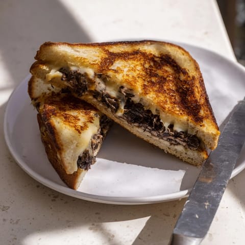 Golden-brown Truffle Grilled Cheese sandwiches with melty Gruyère on a rustic plate.  