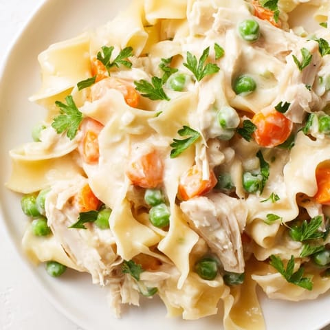 Tender shredded chicken and egg noodles are coated in a creamy sauce with sweet peas and carrots in this Spring Chicken Noodle Skillet.