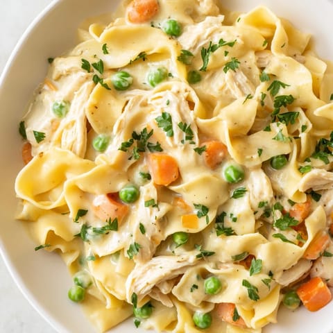 A close-up view of a Spring Chicken Noodle Skillet garnished with fresh parsley, served warm in a rustic skillet for a family dinner.