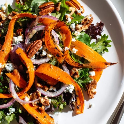 Tender, caramelized carrot ribbons arranged over fresh arugula and spinach, garnished with red onion slices and a sweet tangy dressing.