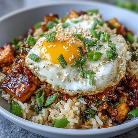 Spicy fermented cabbage kimchi fried rice bowl topped with a sunny-side-up egg.