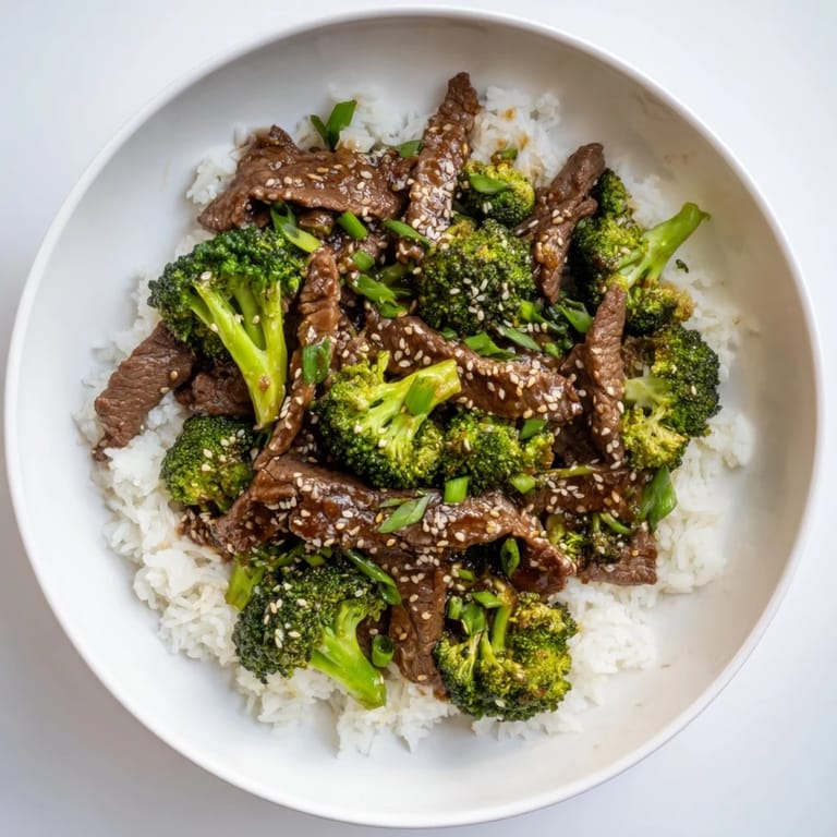 Homemade Beef and Broccoli served over jasmine rice, sprinkled with sliced green onions for extra flavor.