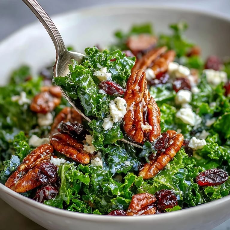 Vibrant, warm kale salad with maple mustard dressing topped with pecans and dried cranberries.