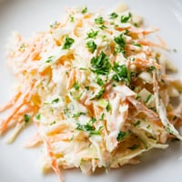 Freshly grated apple adds sweet crunch to a creamy bowl of Coleslaw with Apple, served chilled as a crisp side dish.