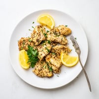 Juicy Lemon Pepper Chicken served hot from the pan, garnished with fresh parsley and bright lemon wedges for a zesty finish.